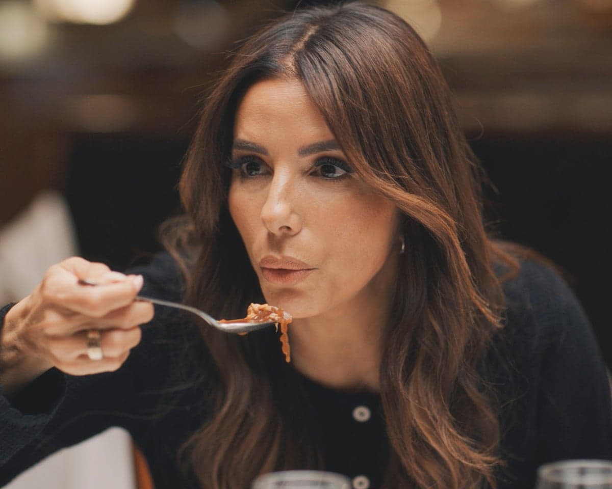 Eva Longoria holds up a spoonful of French onion soup, about to taste it