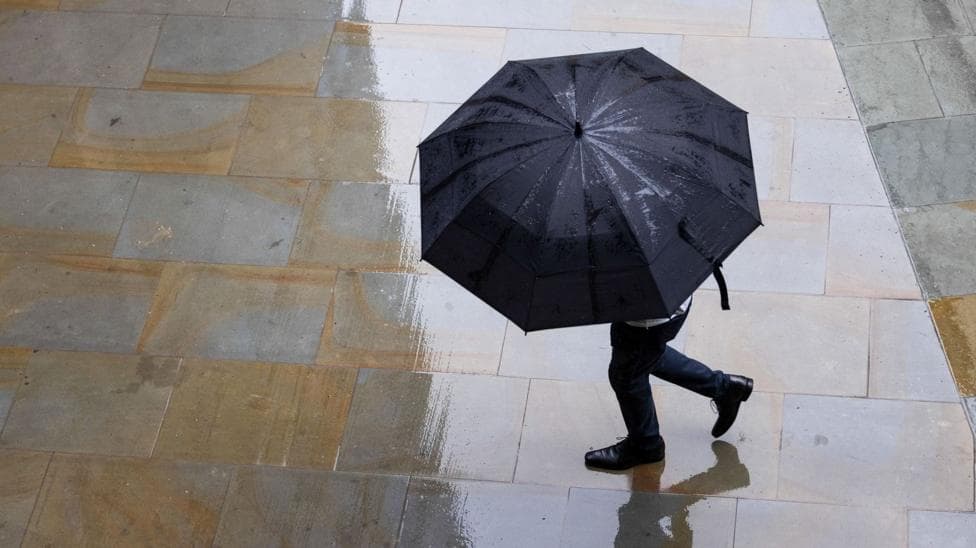 Person under a black umbrella in wet street