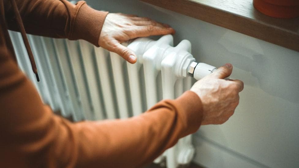 Two hands on a white radiator.