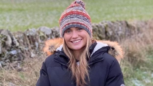 Hannah McInally, a young woman smiling at the camera, in a countryside setting, wearing a warm jacket and warm hat.