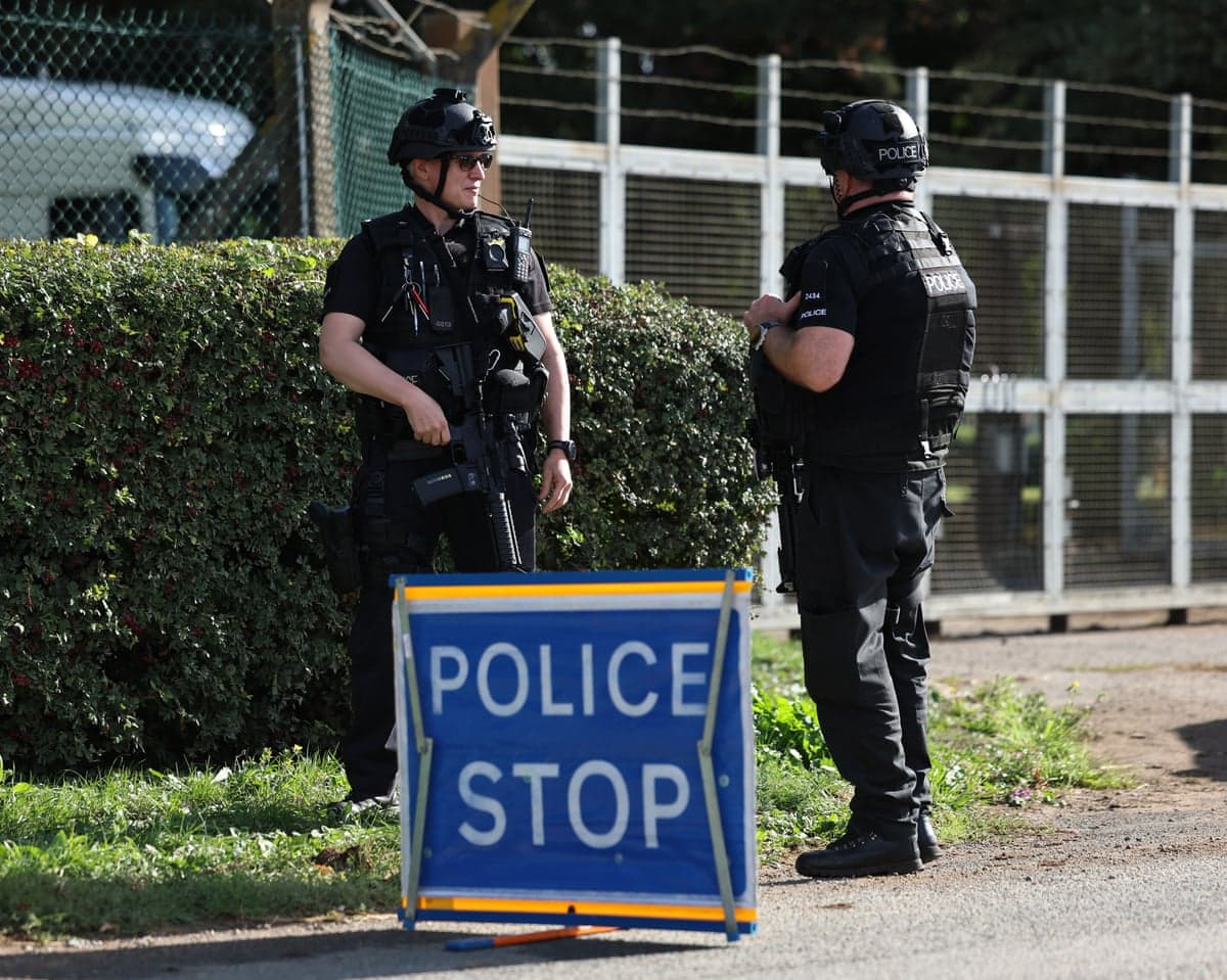 Armed police stand behind a "Police Stop" sign at a cordon outside RAF Fairford