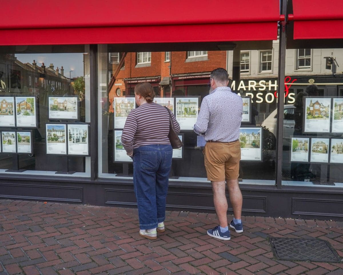 People browsing the window of an estate agent in Wimbledon, southwest London.