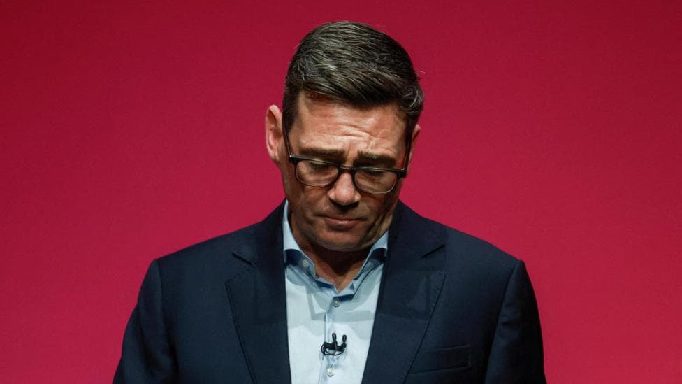 Andy Burnham during his speech to the Labour party conference. He is pictured against a red background, with his head hanging down.