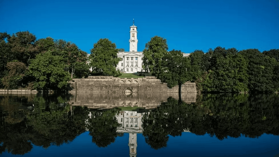 An image of the University of Nottingham surrounded by trees and a lake