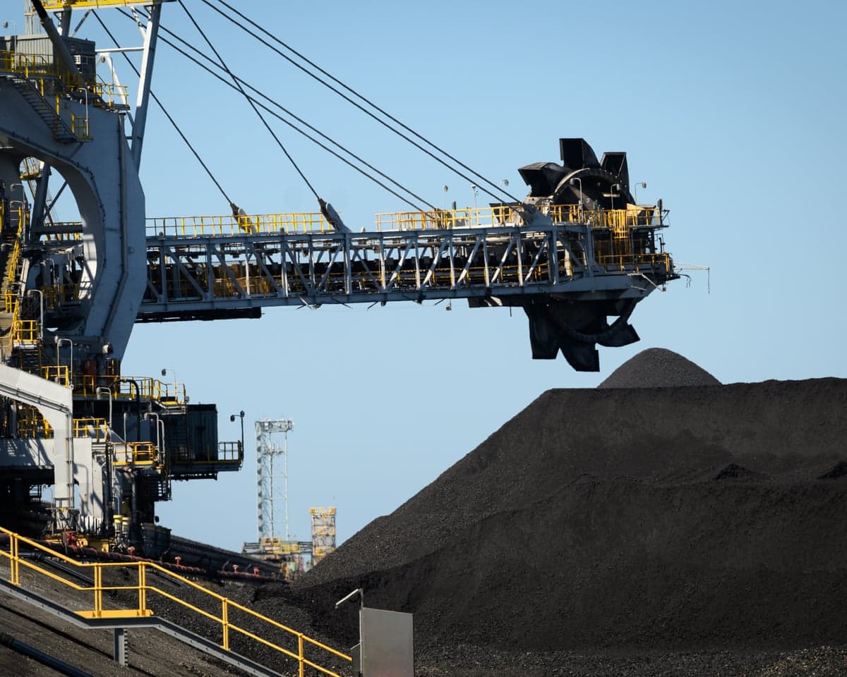 Coal loading machinery deposits material onto a large stockpile at Port of Newcastle