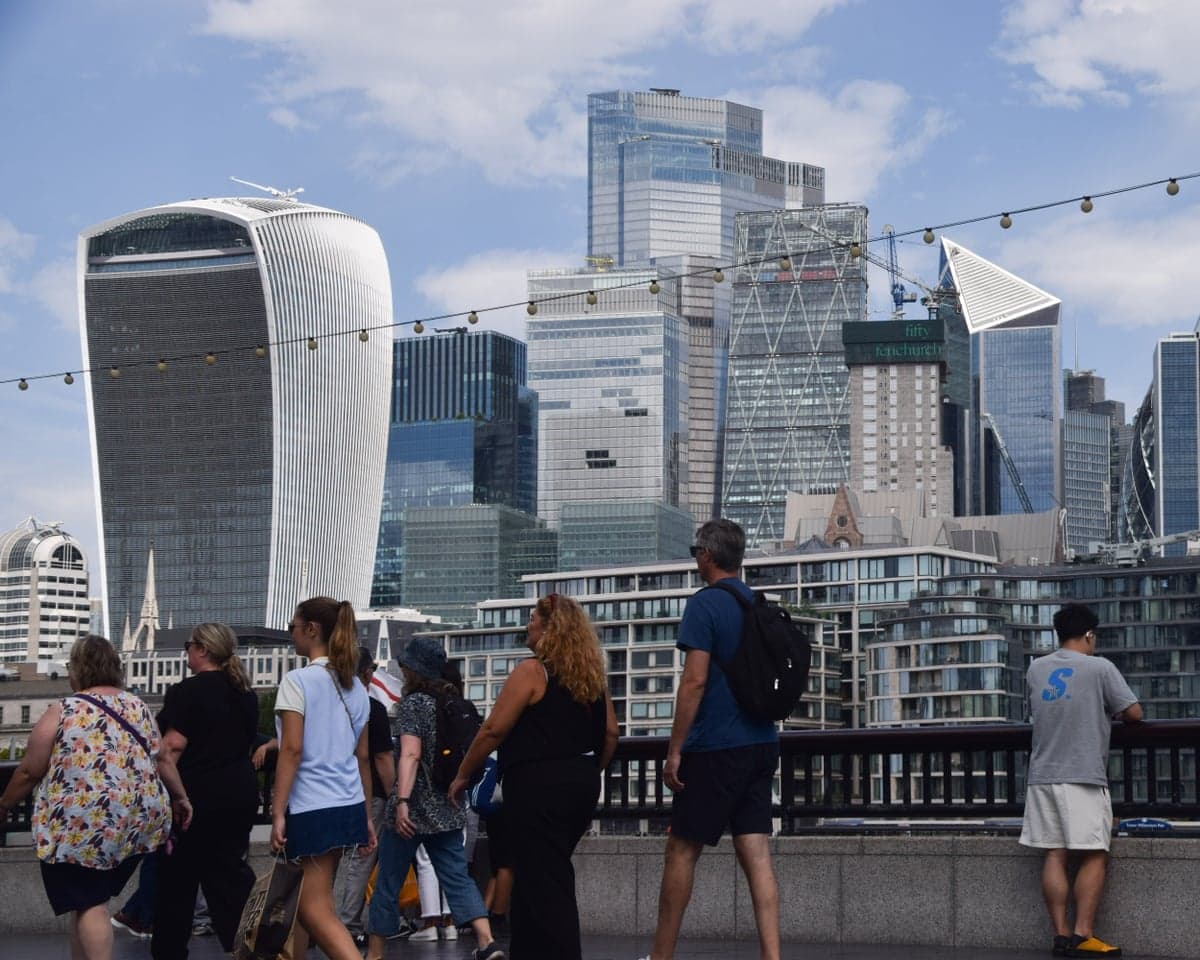 People walk past the City of London skyline