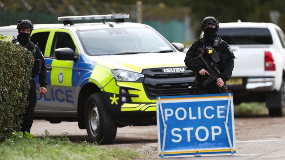 An armed police officer stands guards on a road outside the perimeter of the RAF Fairford airbase