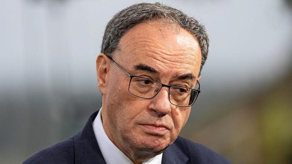 A close up of Bank of England Governor Andrew Bailey looking to one side wearing a navy suit and white shirt