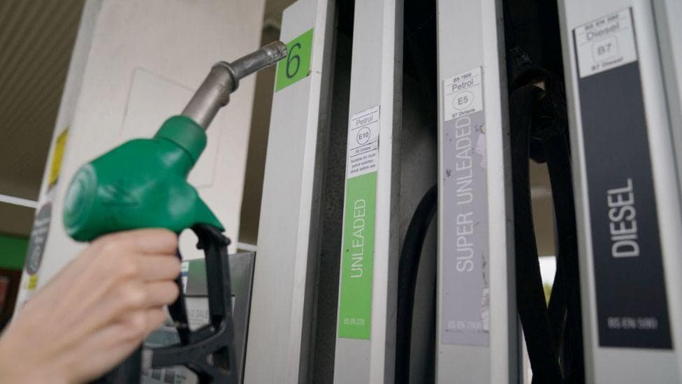 A petrol pump hose being taken from the pump