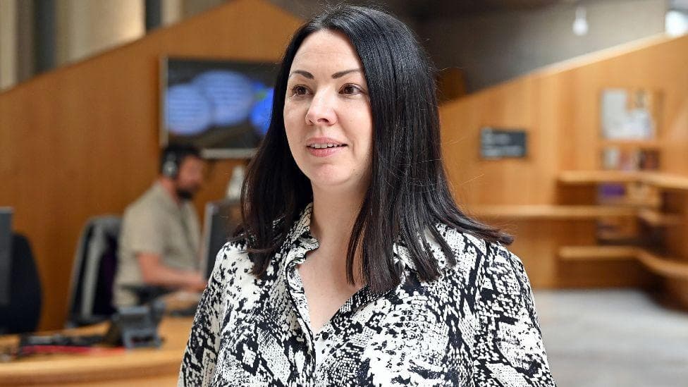 Monica Lennon, who has long black hair, wearing a patterned black and white shirt