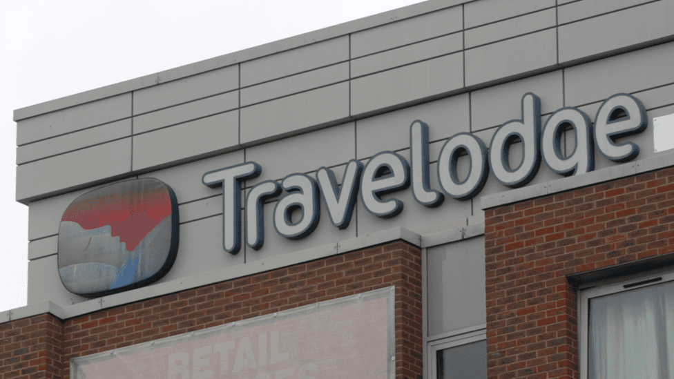 A shot of the Travelodge logo on one of a hotel building.