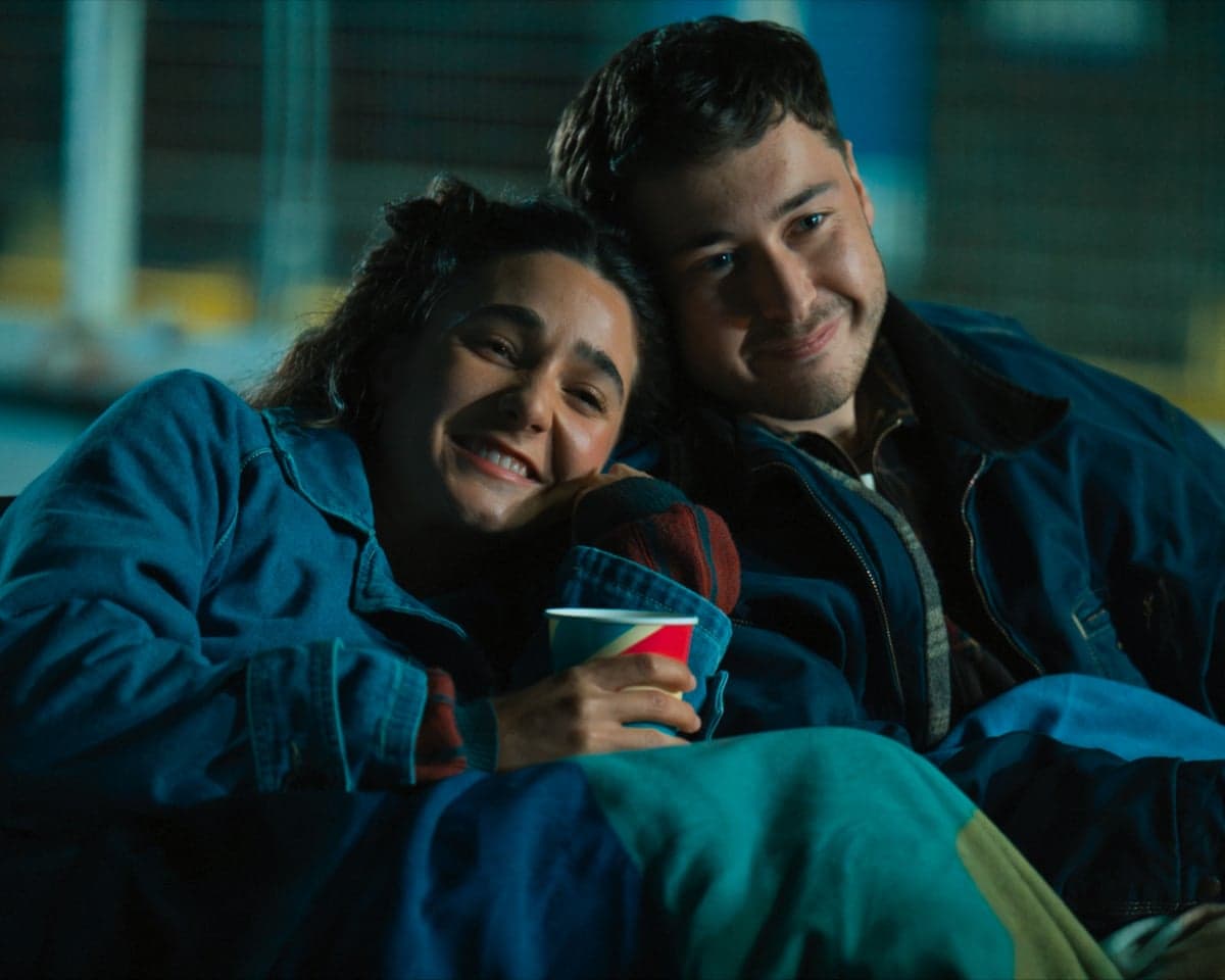 Lil and Ben smile together She has her head on his shoulder and she is holding a drinking cup