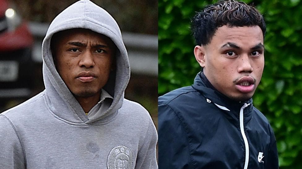 Two men, pictured side by side. The man on the left is wearing a grey hoodie with the hood up. The man on the right has a navy Nike jacket on. He has short black hair.