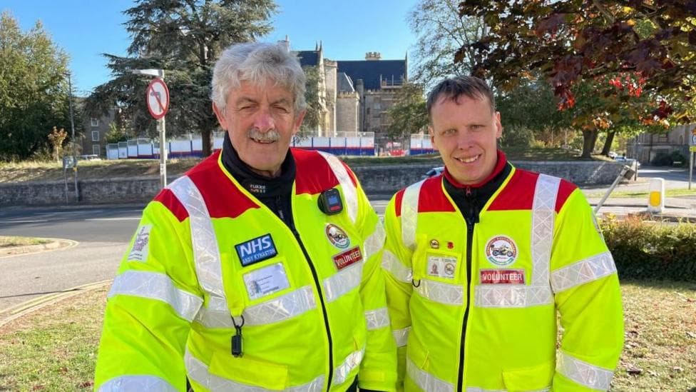 Two men wearing yellow high vis jackets with a red trim.