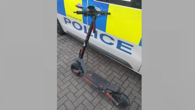 an e-scooter propped against the door of a police van