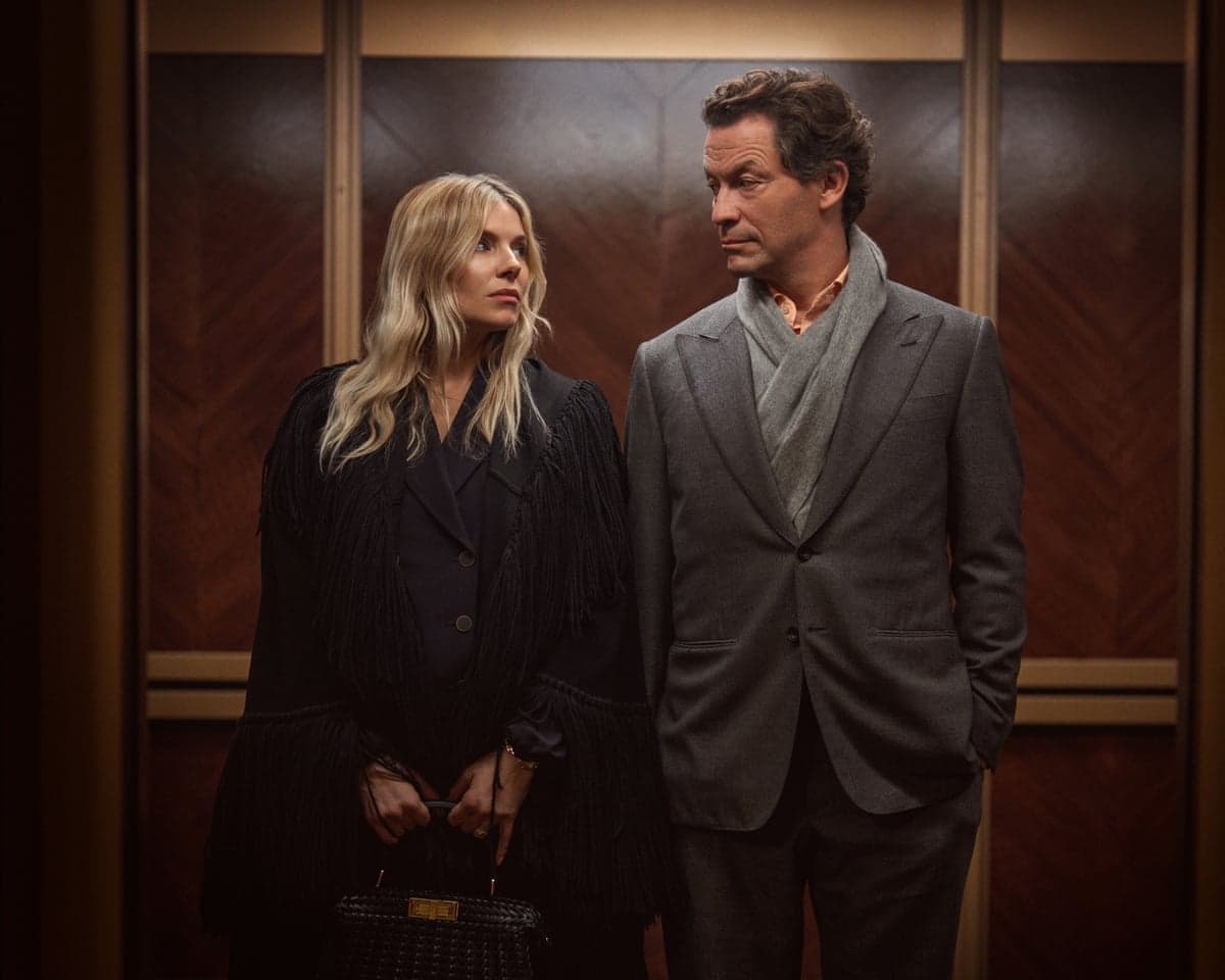 A well-dressed man and woman turn to face each other in a wood-panelled lift