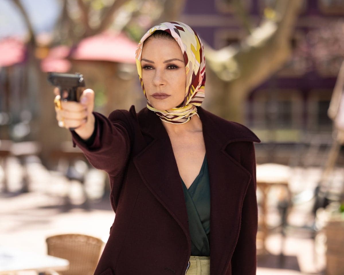 Catherine Zeta-Jones, as Jackie Price, points a handgun outdoors