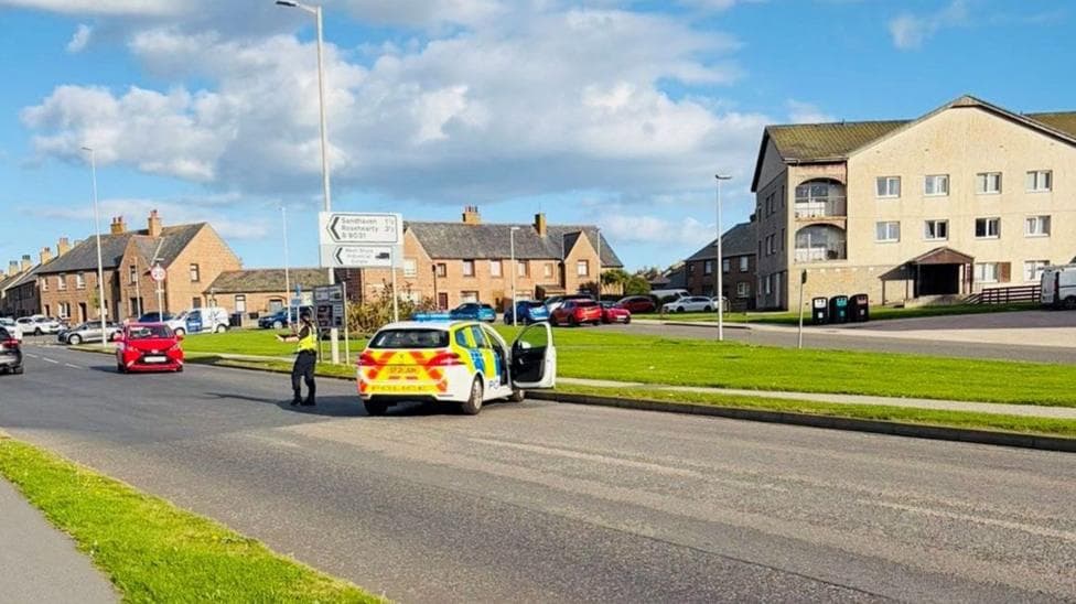 Police at the scene of a road traffic collision on Watermill Road in Fraserburgh, with traffic being directed past the incident area.