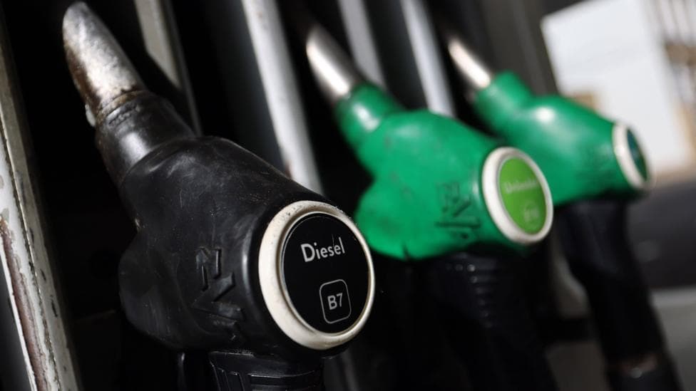 A close-up image of a black diesel pump and two green petrol pumps.