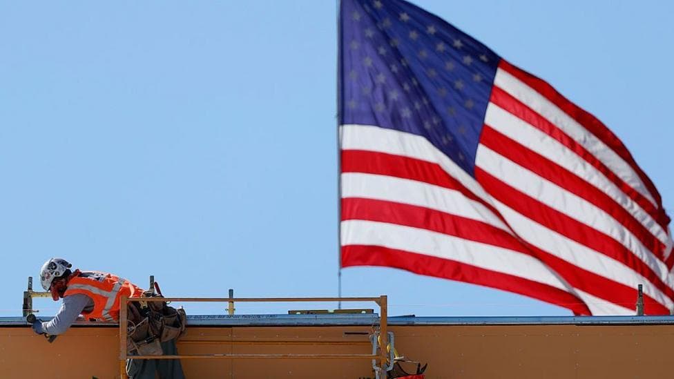 An American flag flies near a construction worker during construction of a new building on 6 March 6, 2026 in Pasadena, California.