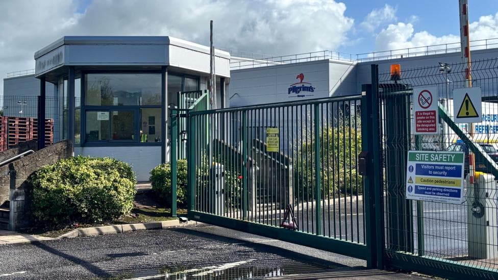 The Pilgrim's factory in Enniskillen. It is a grey building with a glass window, there are green gates at the front.
