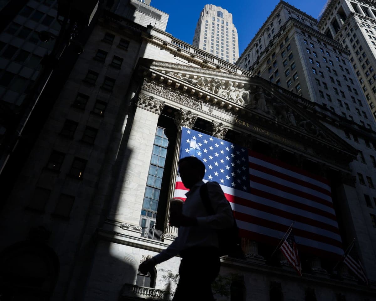 Someone walking past the New York Stock Exchange with the US flag displayed