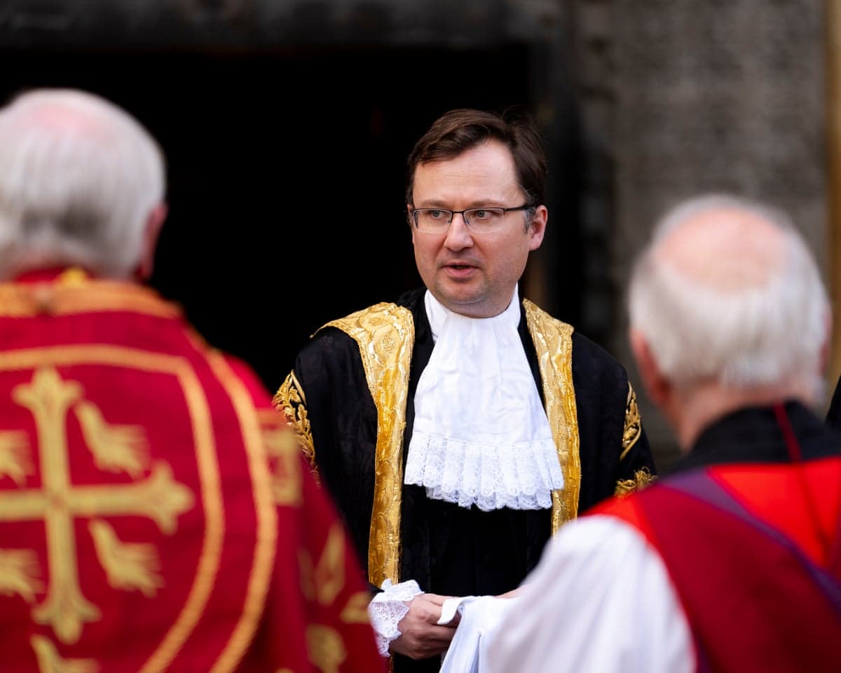 Alex Norris wearing a black and gold gown leaves Westminster Abbey.