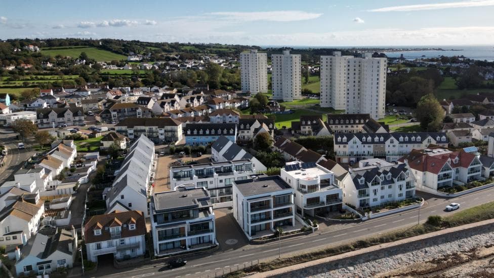 An aerial image of St Clements in Jersey. It features a seafront and multi-storey properties. In the background is the sea and green fields.