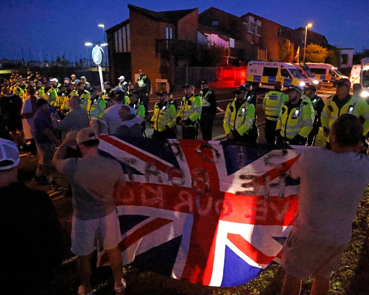 Police in high-visibility vests face protesters holding a Union flag during a Gosport demonstration