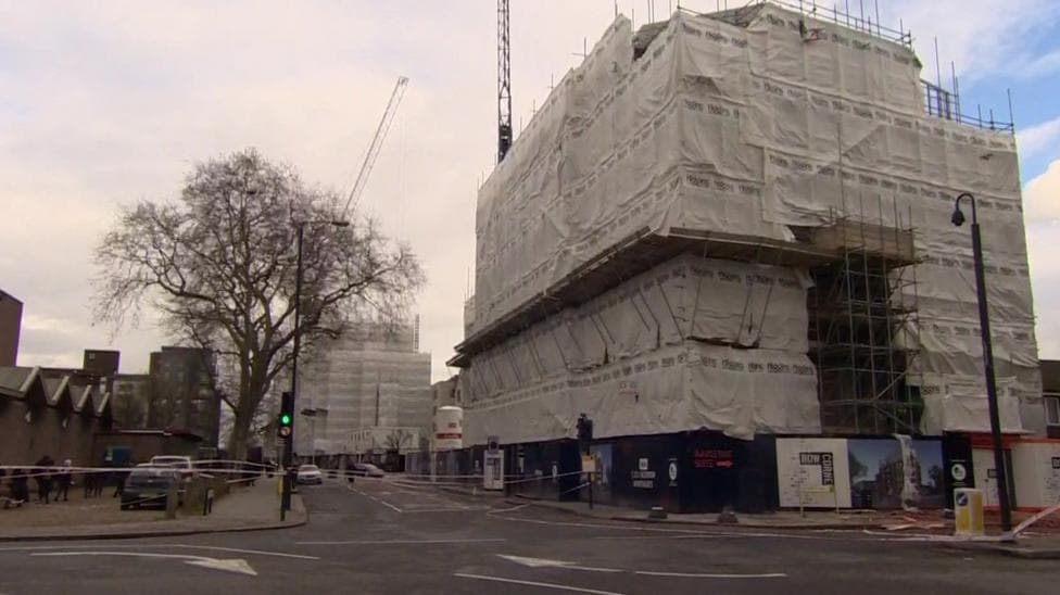 Two large buildings covered in tarpaulin and scaffolding - the building site where the accident happened.