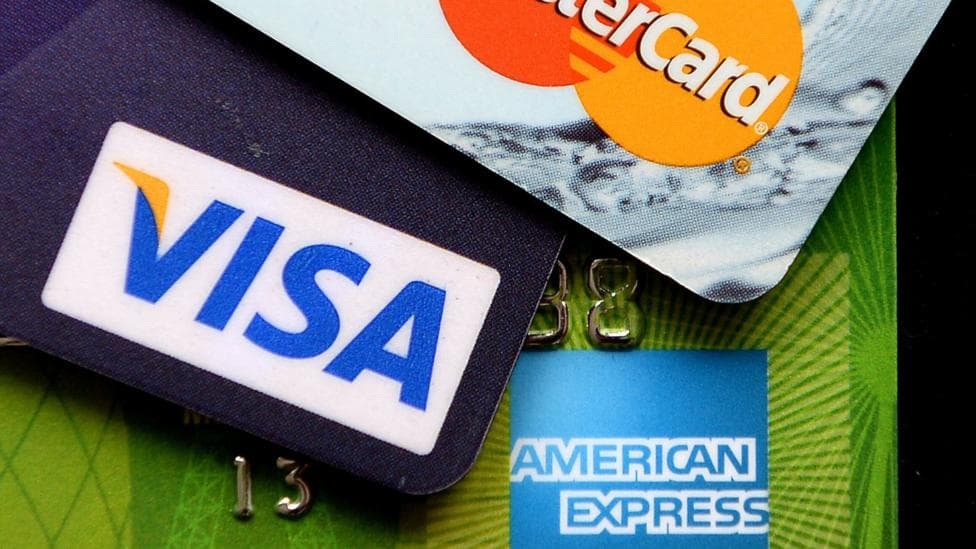Close-up three credit cards that say Visa, American Express and MasterCard.