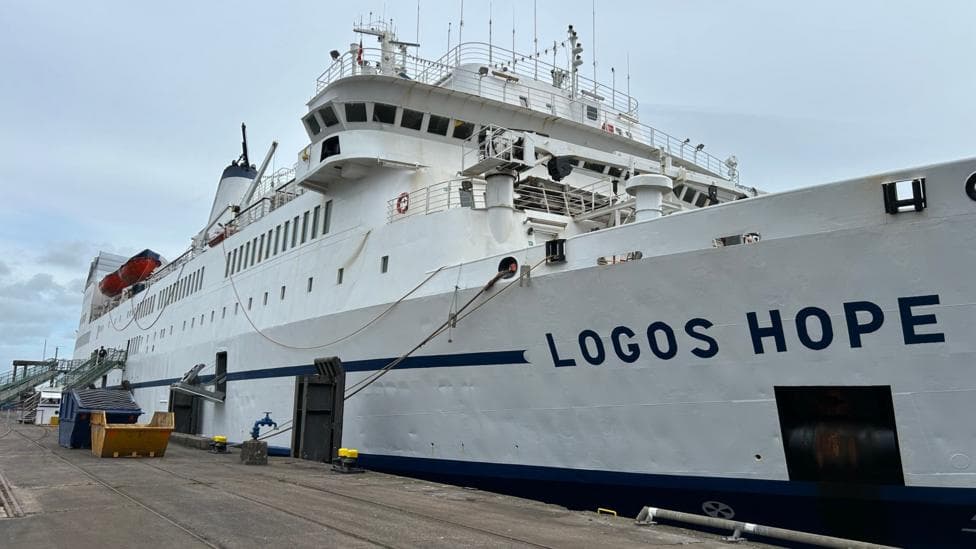 A large ship with a white and blue exterior and the words 'LOGOS HOPE' painted on the side