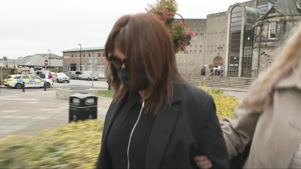 A woman with dark hair, sunglasses and wearing a mask