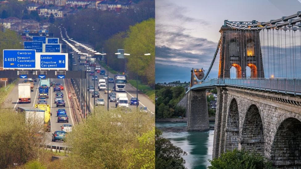 A shot of the M4 on the left, with cars visible on both sides of the motorway, and the Menai Bridge on the right hand side.