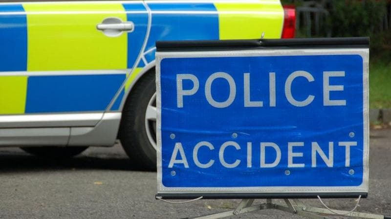 Blue Police Accident sign with white writing. It is on a road in front of a police car