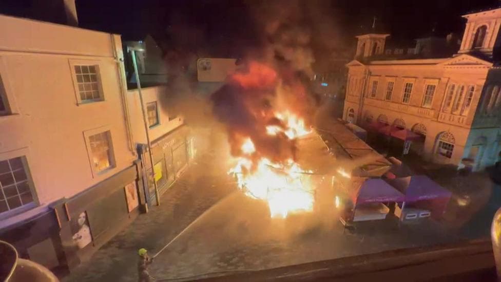 Firefighters use a hose to put out the large market fire
