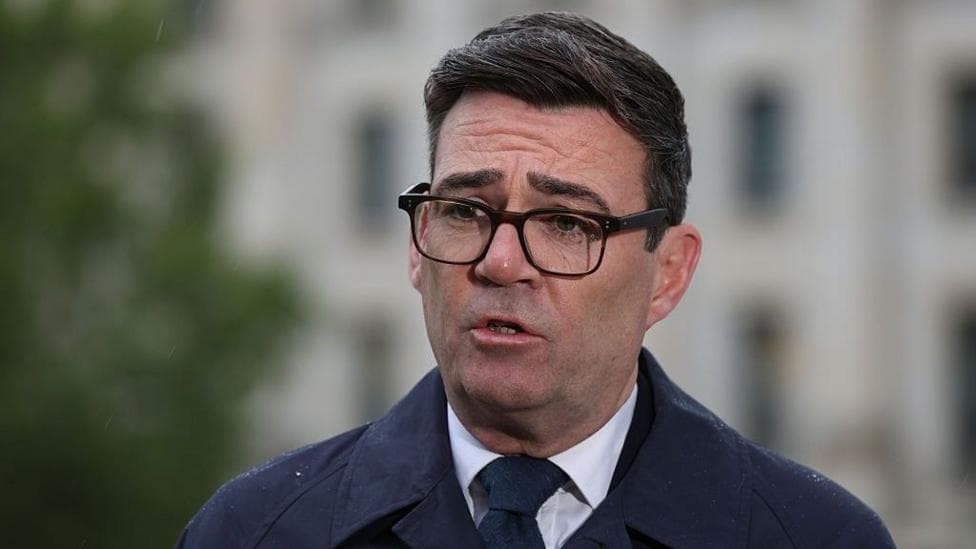 Andy Burnham, wearing a dark suit, recording a media interview in Berlin