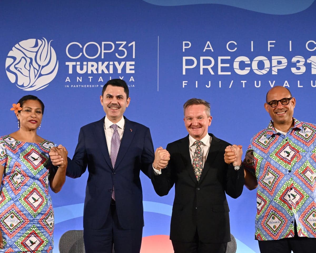 Lynda Tabuya, Murat Kurum, Chris Bowen and Simon Stiell smile as they stand in a row clasping hands