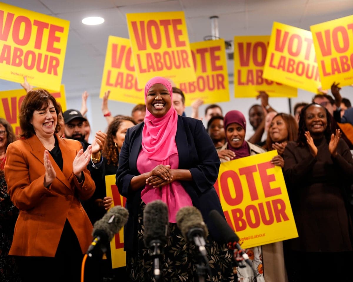 Powell and Abdi-Wali smile as supporters surround them with 'Vote Labour' placards