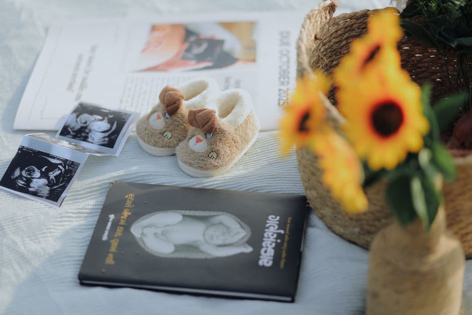 Flat lay of baby shoes, sonogram, and sunflowers, symbolizing pregnancy announcement.