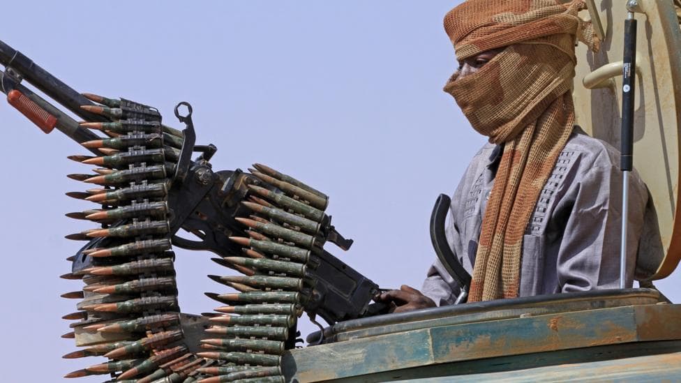 File photo of a defector from the RSF standing in an armed vehicle with a mounted gun and a chain of bullets.