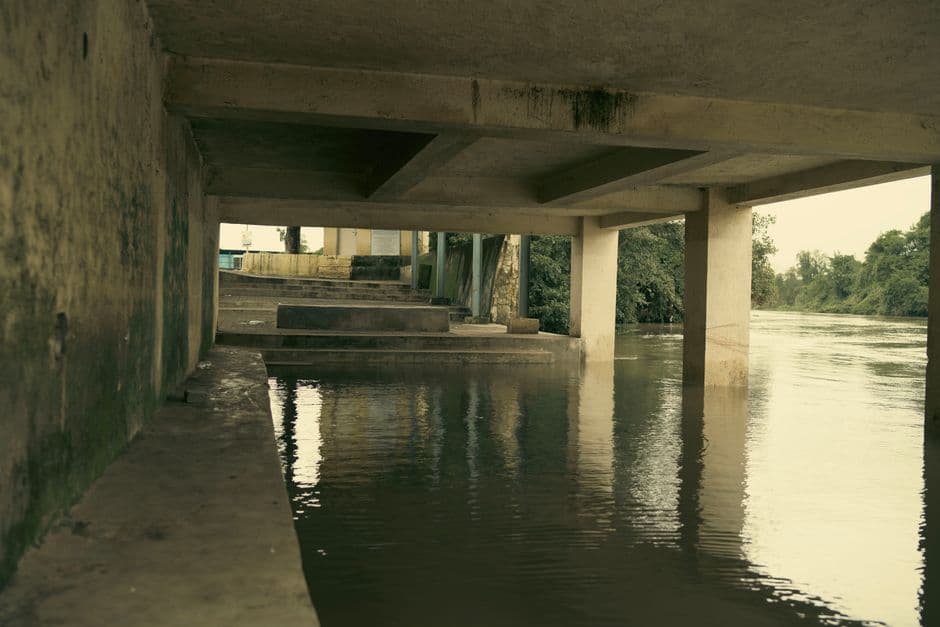 An artistic view of a concrete structure over a calm, flooded river.