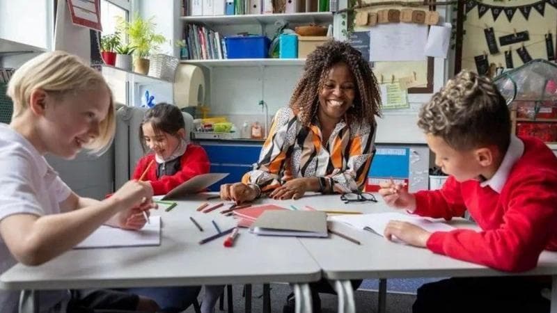 A group of children with a teacher sat at a table in a school.