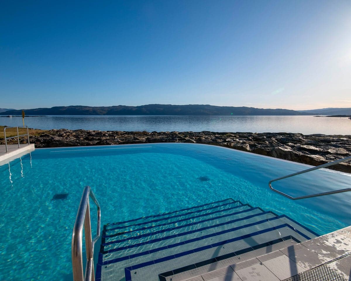An infinity pool looking over a loch and sunny blue sky with the Isle of Arran in the distance
