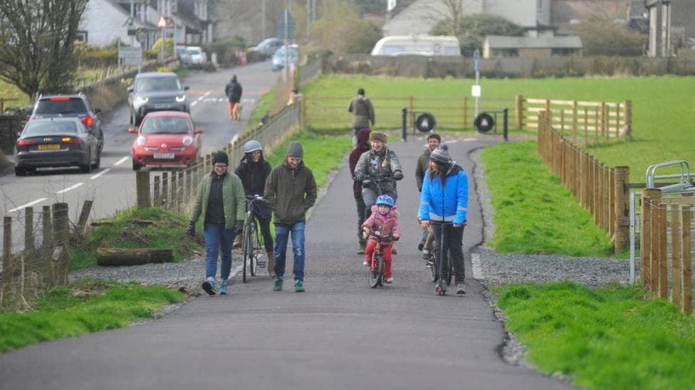 A group of people using a cycle path next to a roadway