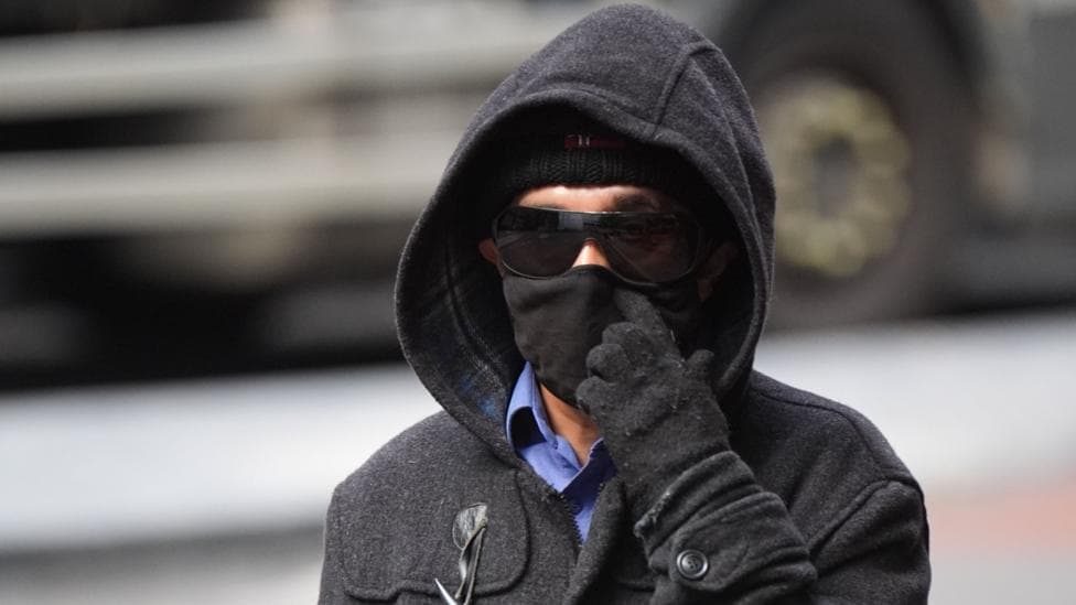 A 55-year-old man wears sunglasses, a hat, hood and gloves as he arrives at court.
