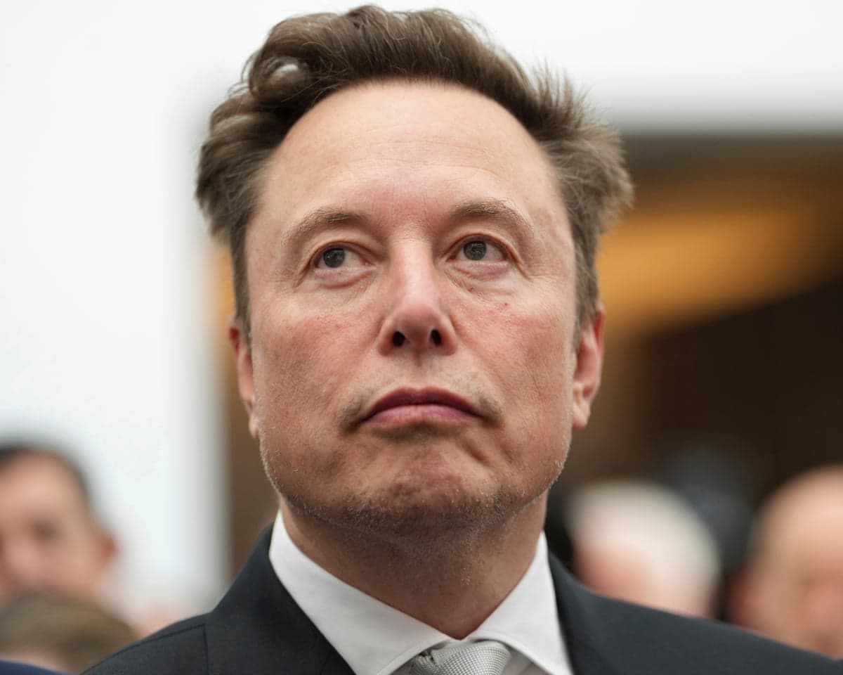 Elon Musk looking upwards as he listens to a speech