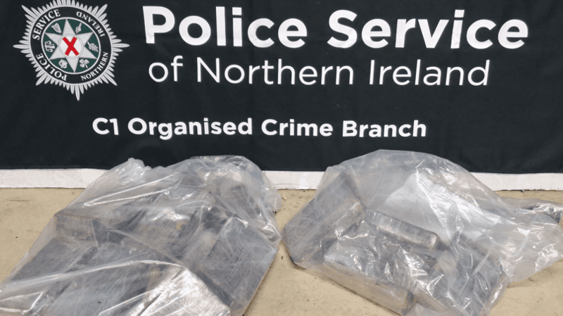 A PSNI banner and two large clear plastic bags containing blocks of drugs.