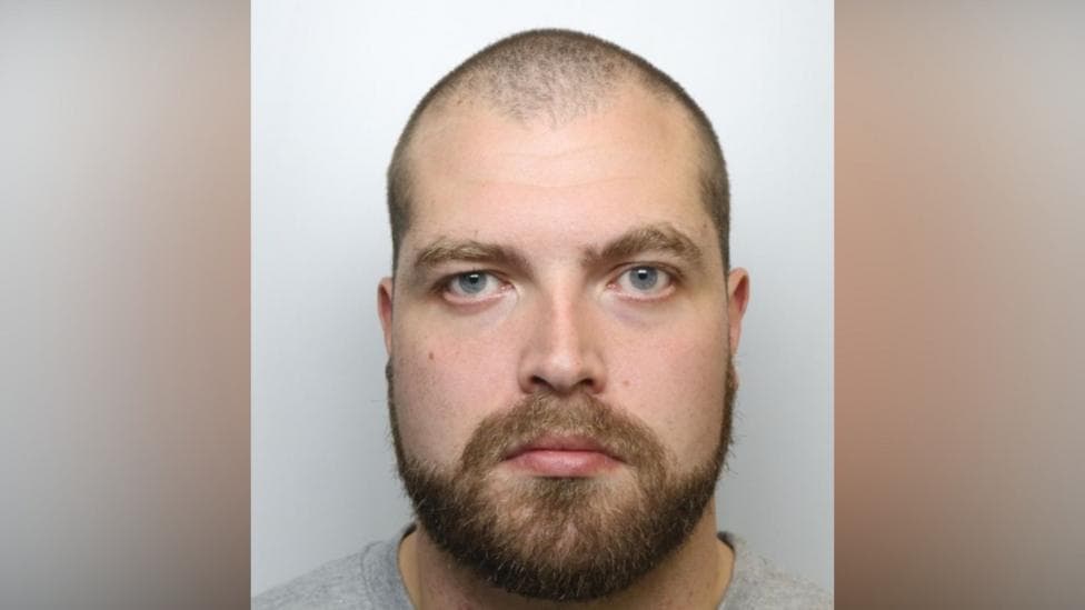 Headshot of Mark Broadhurst, who has shaved head, blue eyes and brown beard