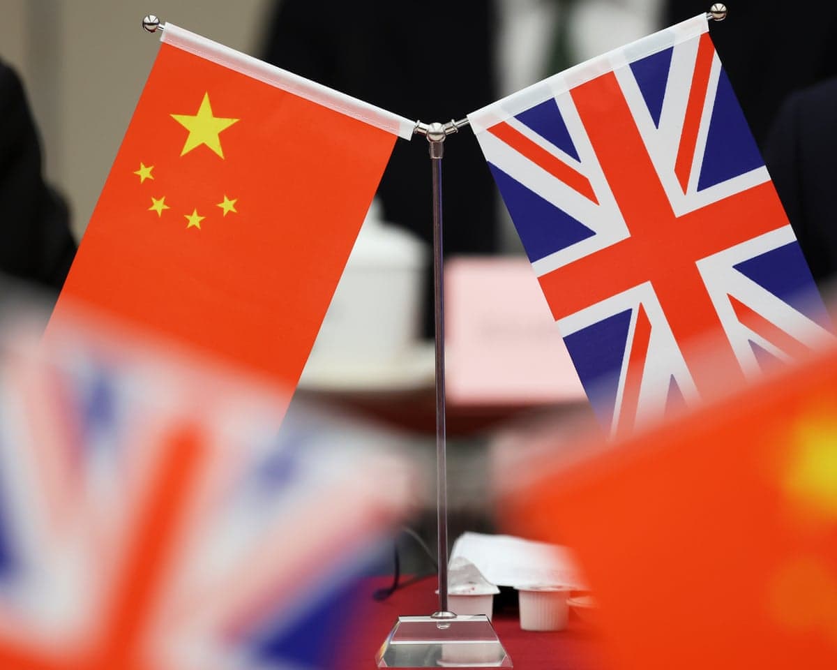 Small table flags of China and the United Kingdom stand side by side on a crossed pole stand